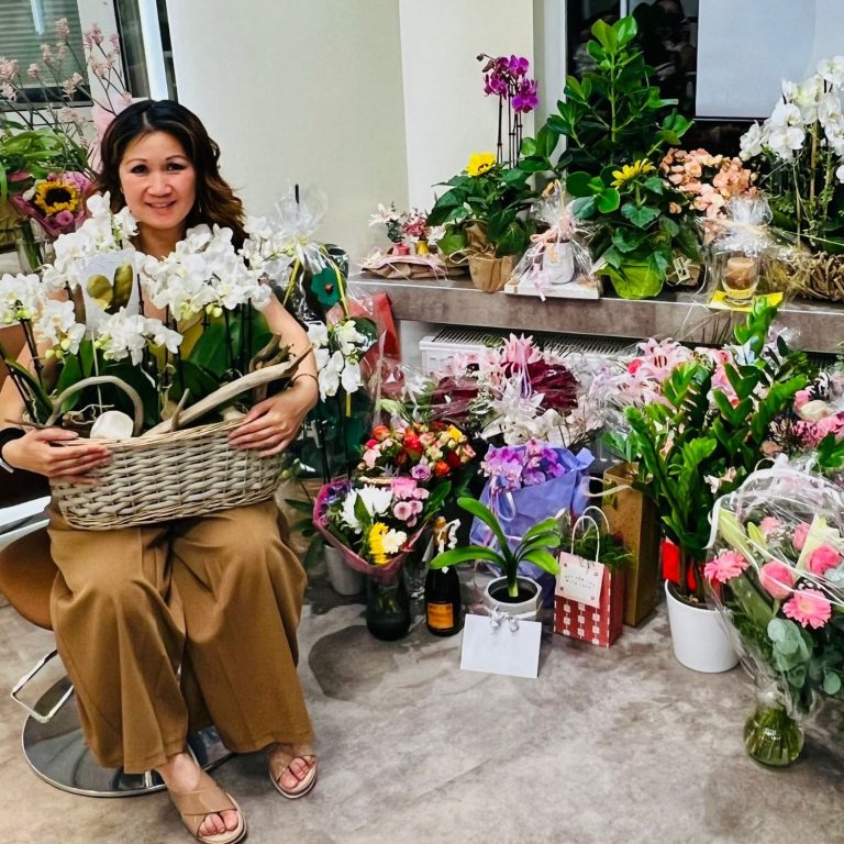 hier sitzt Le Binh in mitten von vielen Blumen, die sie zur Eröffnung geschenkt bekommen hat.